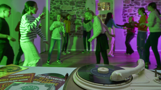 Jugendliche tanzen, im Vordergrund ein alter Schallplattenspieler