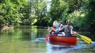 Gruppe fährt mit Kanu auf einem Fluss