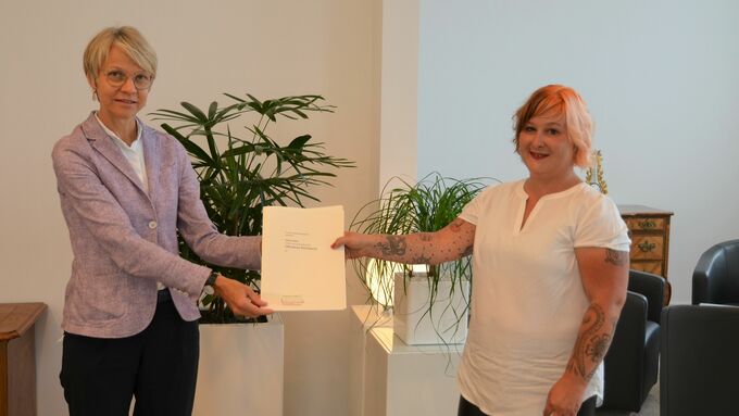 Regierungspräsidentin Dorothee Feller (links) überreicht die Belobigungsurkunde an Janine Giese (rechts) aus Datteln