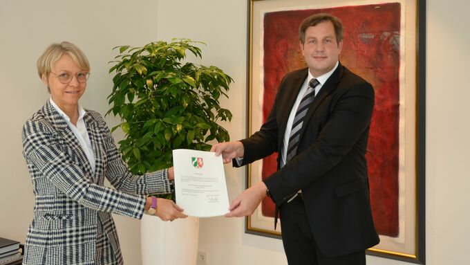Regierungspräsidentin Dorothee Feller (links) überreicht die Anerkennungsurkunde für die „Virchow Foundation für Globale Gesundheit“ an Roland Göhde