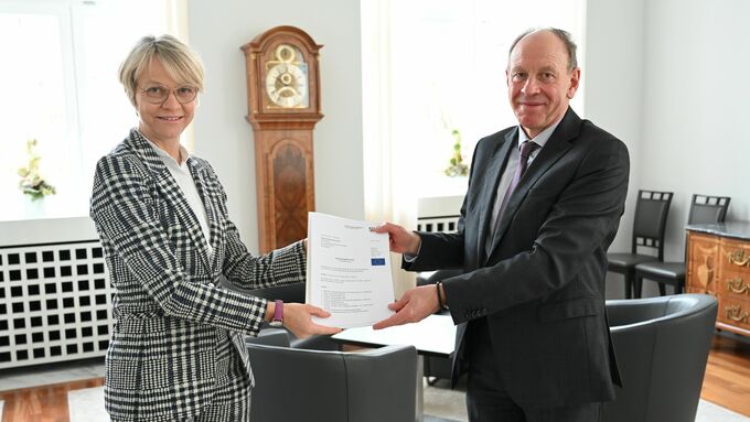 Regierungspräsidentin Dorothee Feller (links) übergibt einen Förderbescheid an Bottrops Oberbürgermeister Bernd Tischler (rechts)