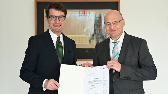 Regierungspräsident Andreas Bothe (l.) übergibt den Förderbescheid an den Landrat des Kreises Steinfurt Dr. Martin Sommer (r.).