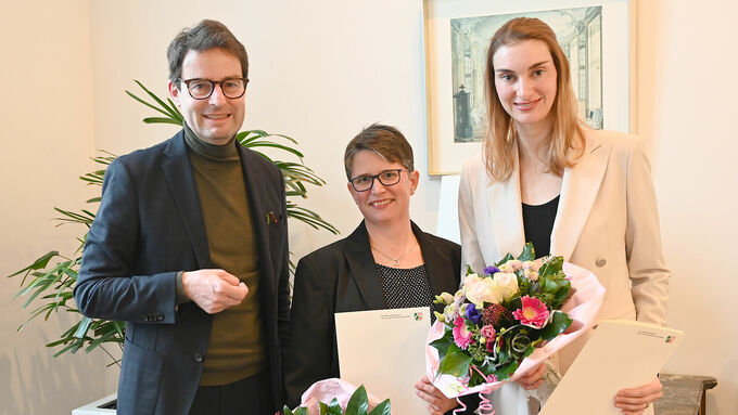 Regierungspräsident Andreas Bothe (l.) überreicht die öffentlichen Belobigungsurkunden an Dr. med. Rebekka Falkner (M.) und Anna von Eiff (r.).