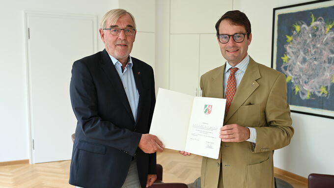 Regierungspräsident Andreas Bothe (r.) übergibt die Anerkennungsurkunde an Josef Vennekötter, der zum anfänglichen Stiftungsvorstand der Jugendstiftung des SV Union Wessum gehört.