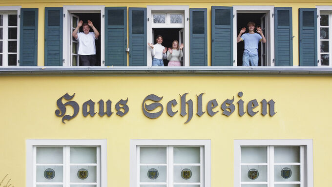 Jugendliche stehen in Fenstern von Haus Schlesien