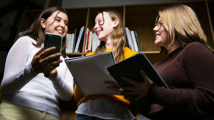 Jugendliche arbeiten in einer Bibliothek mit smartphone und tablet