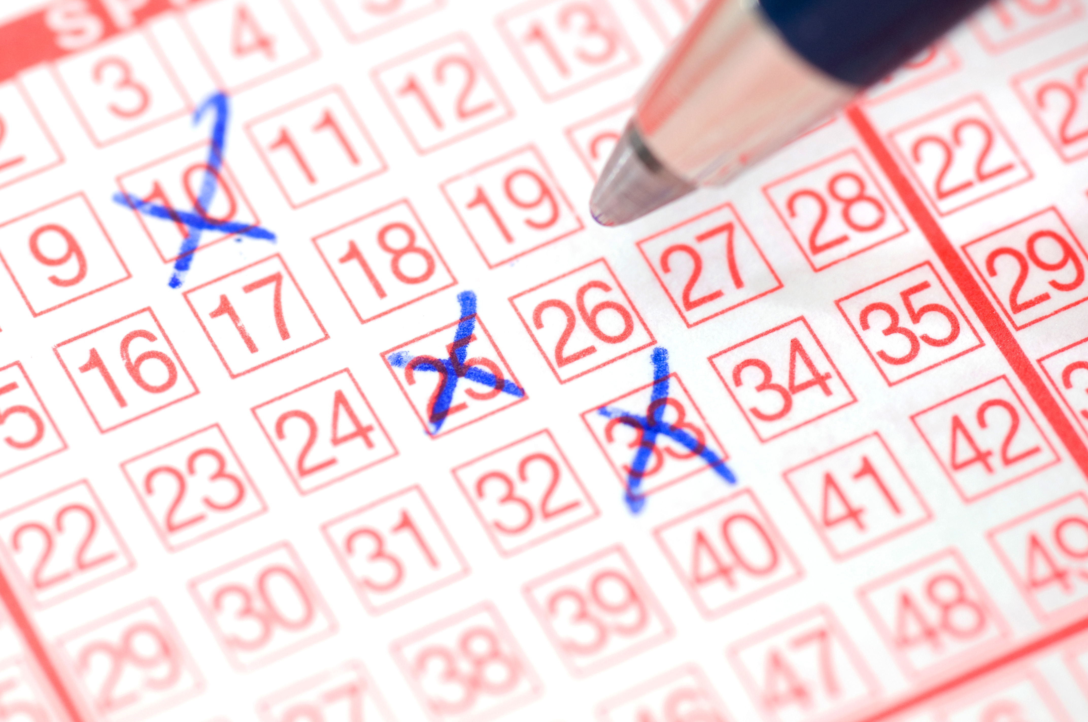 Ein Stift setzt Kreuze auf einem Lotterieschein. 