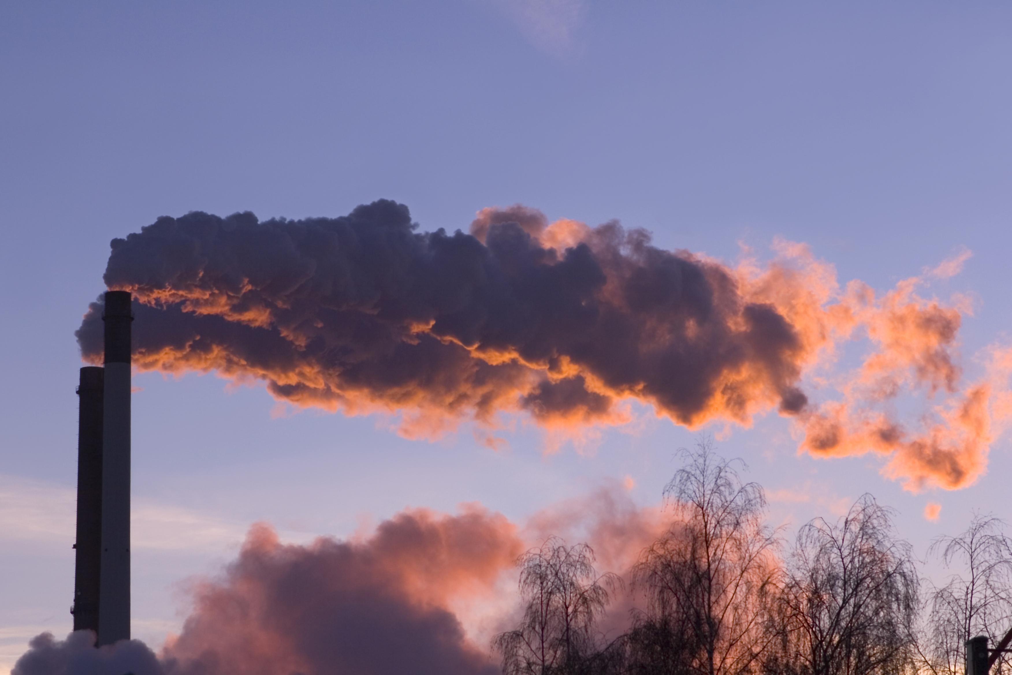 Qualm weht aus einem industriellen Schornstein im Sonnenuntergang