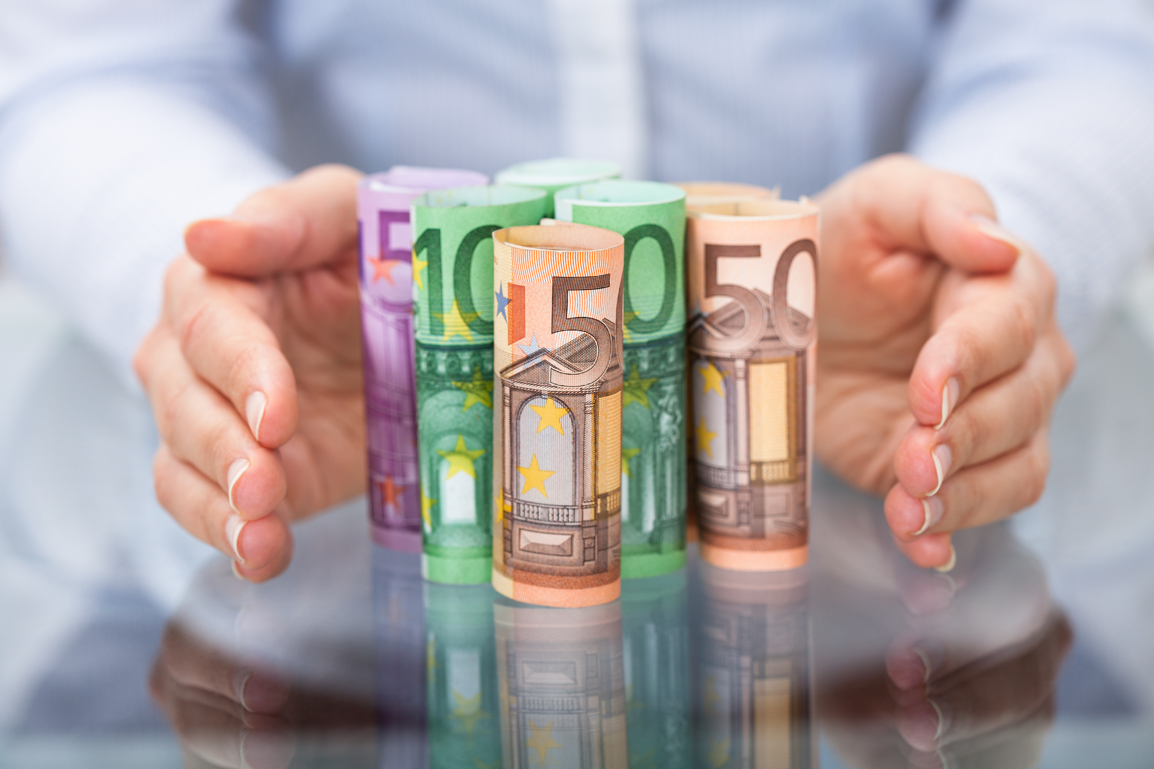 Zwei Hände stehen schützend um Bargeld