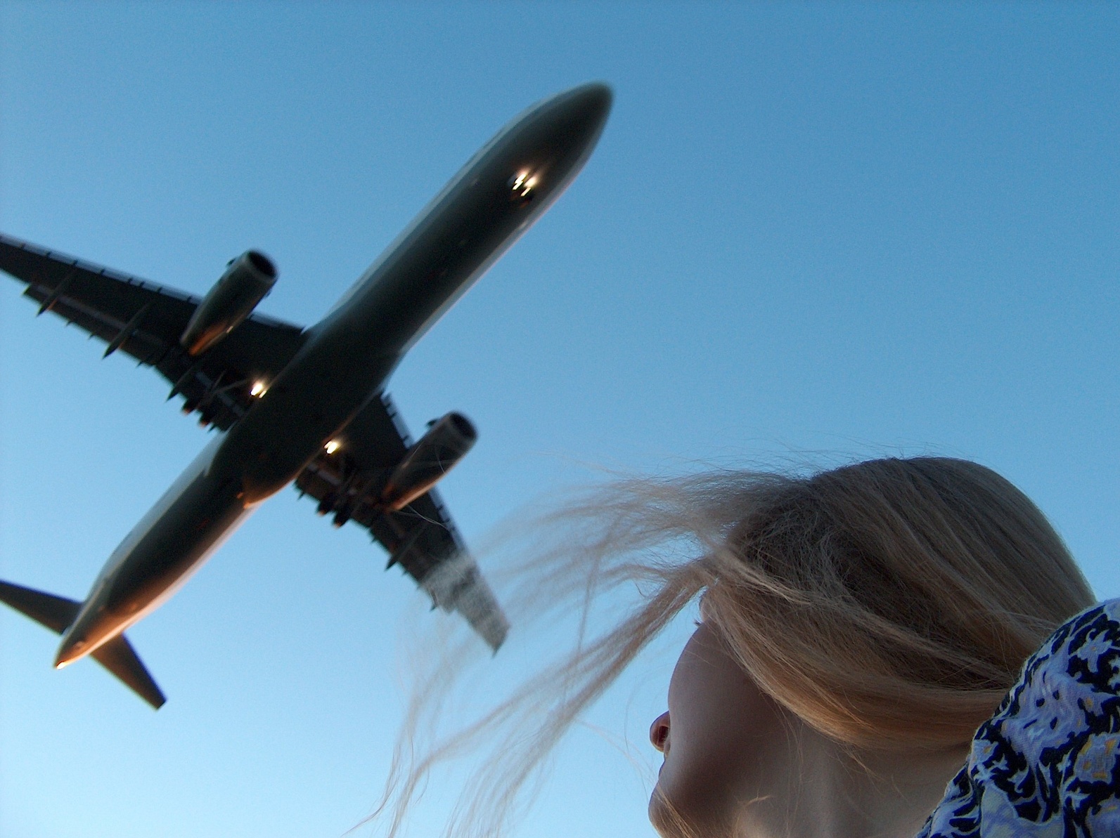 Eine Frau schaut auf ein über ihr fliegendes Flugzeug