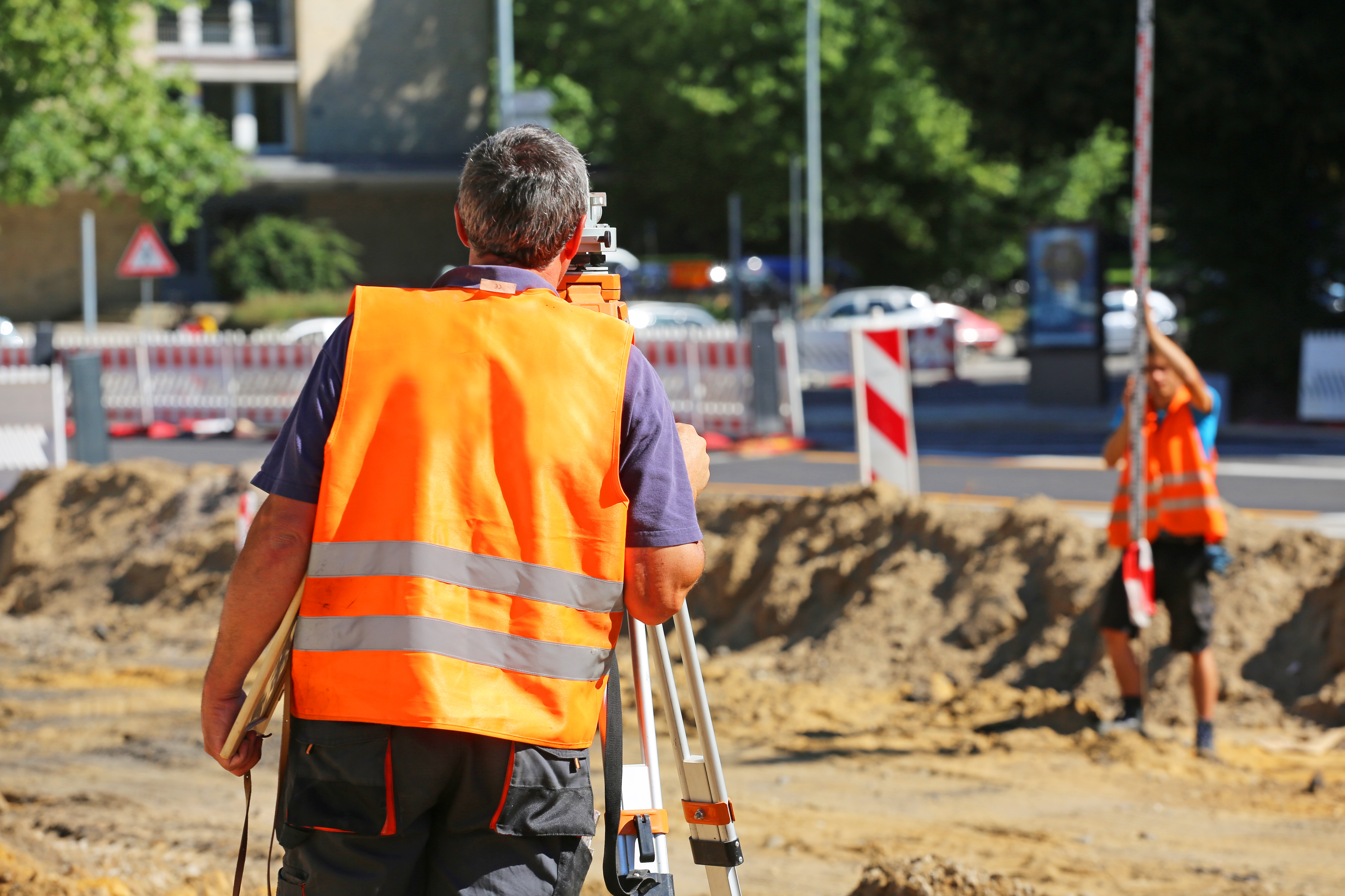Vermesser mit Warnweste auf Straßenbaustelle
