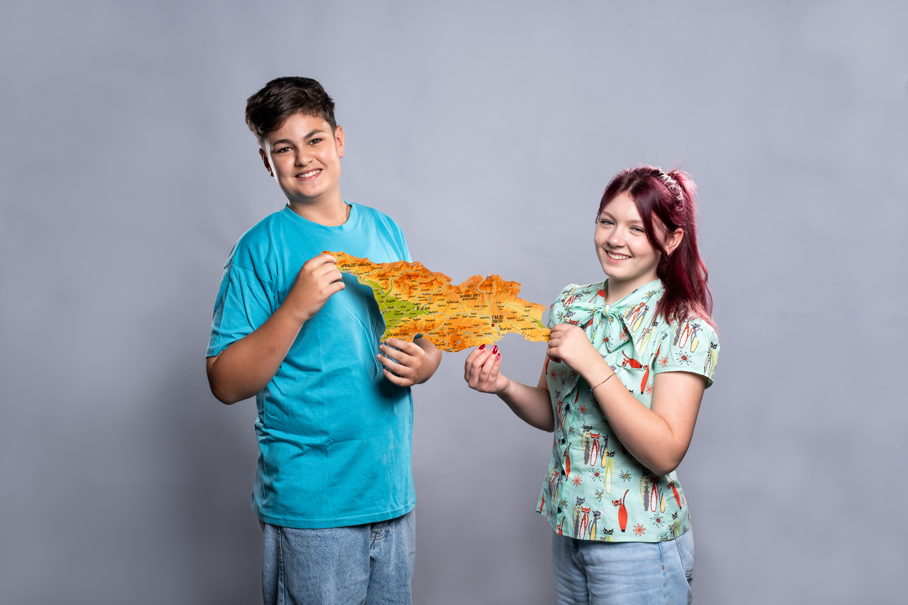 Zwei Jugendliche halten die Kartenumrisse von Georgien