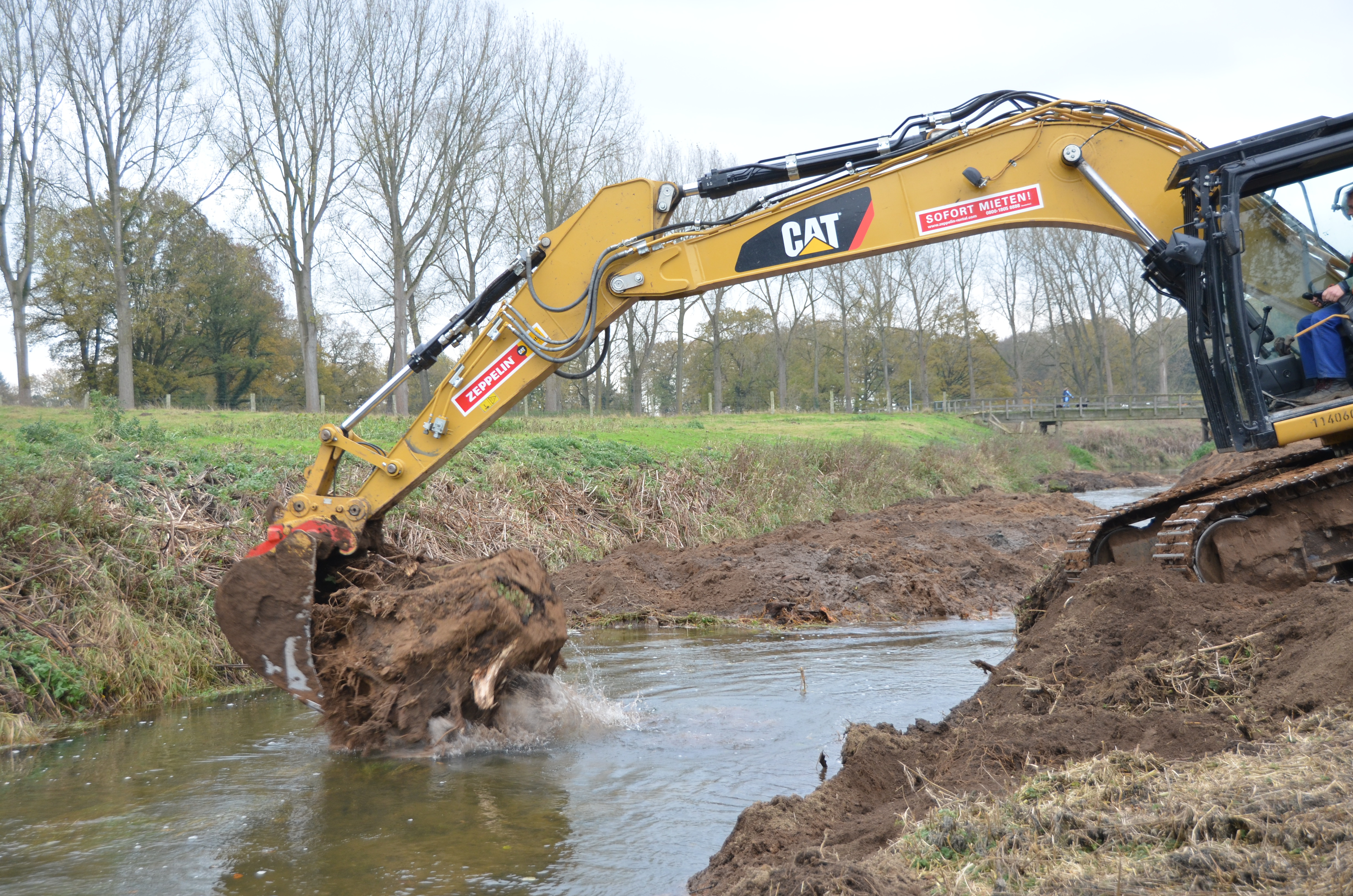 Der Bagger bringt Stubben als Totholzelement ein 