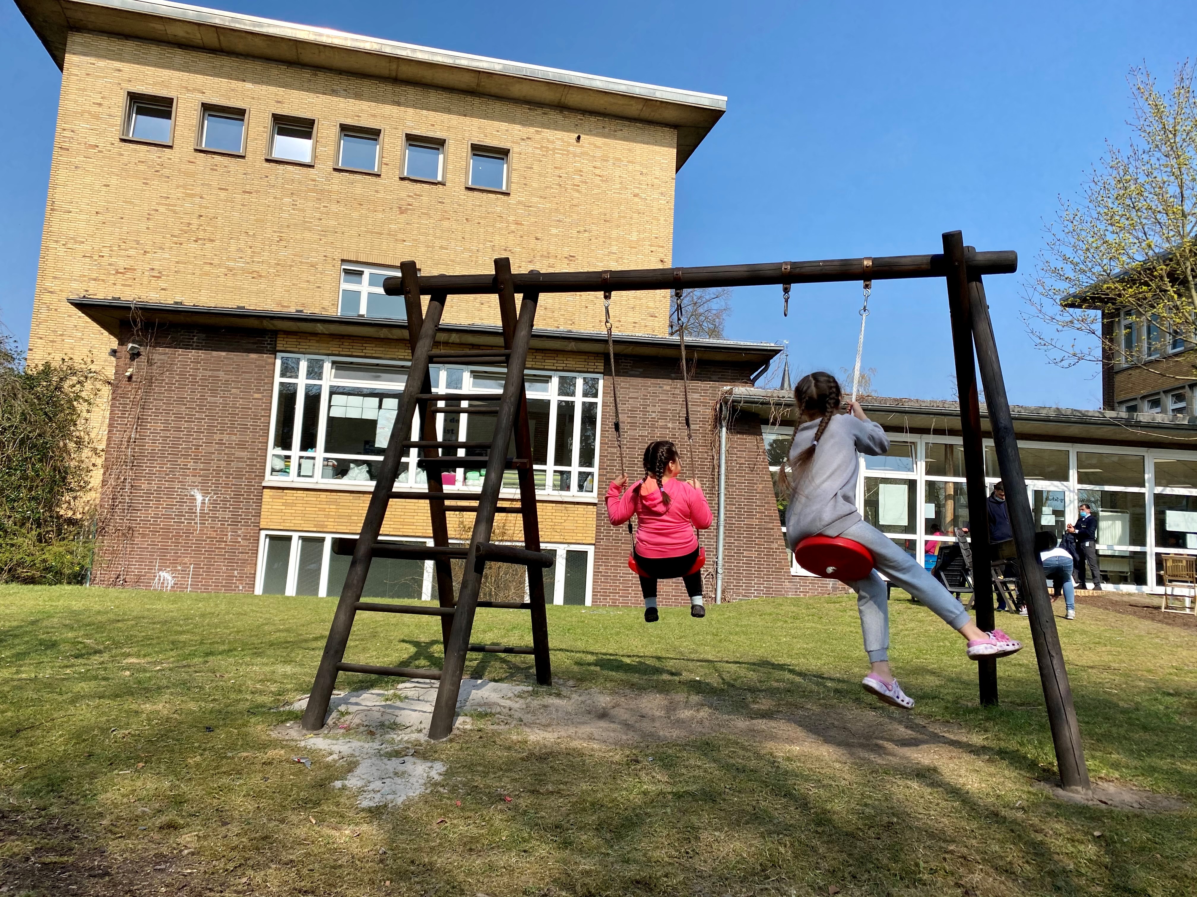 Zwei Mädchen schaukeln vor einer Unterkunft