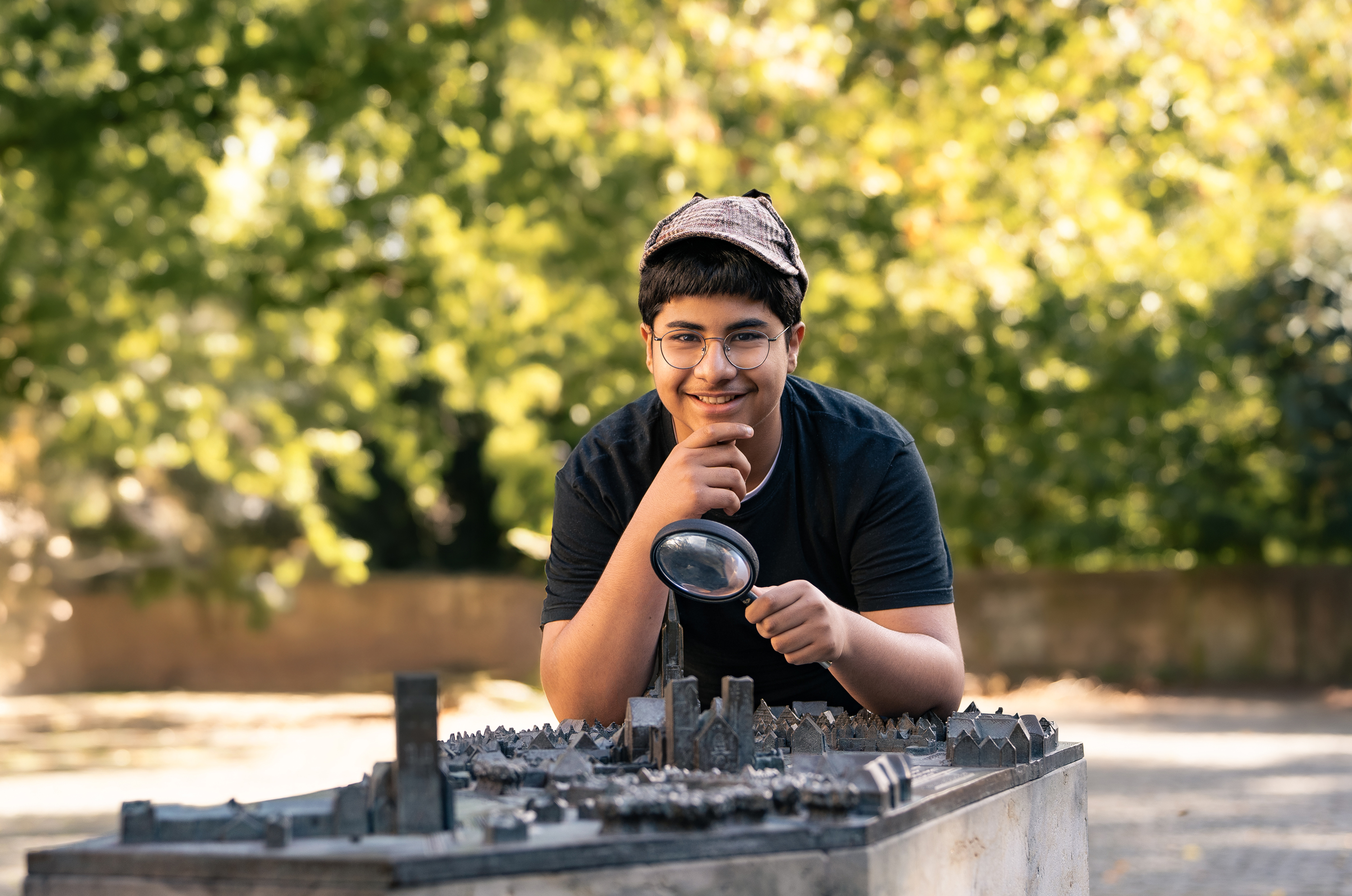Ein Junge schaut - mit einer Lupe in der Hand - auf ein 3D-Modell von Münster 