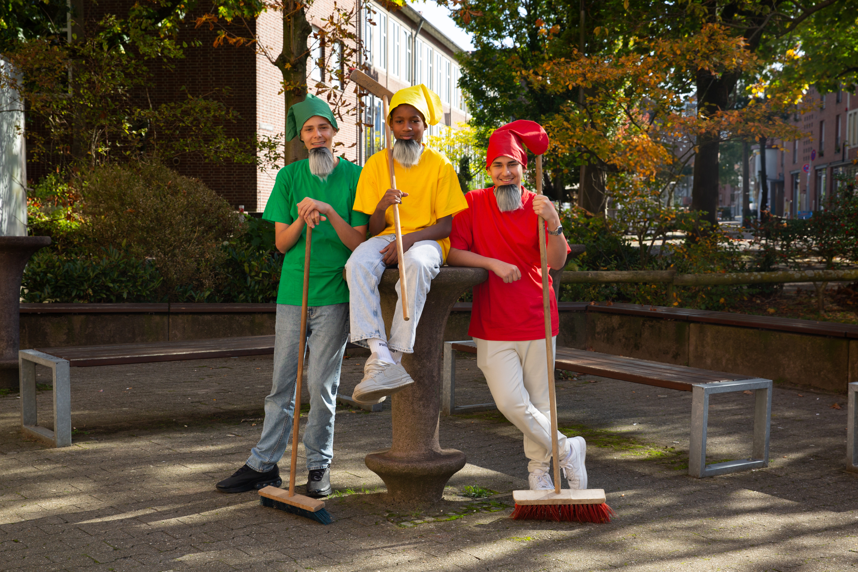 Drei männliche Jugendliche sind als Märchenzwerge verkleidet und halten Besen.