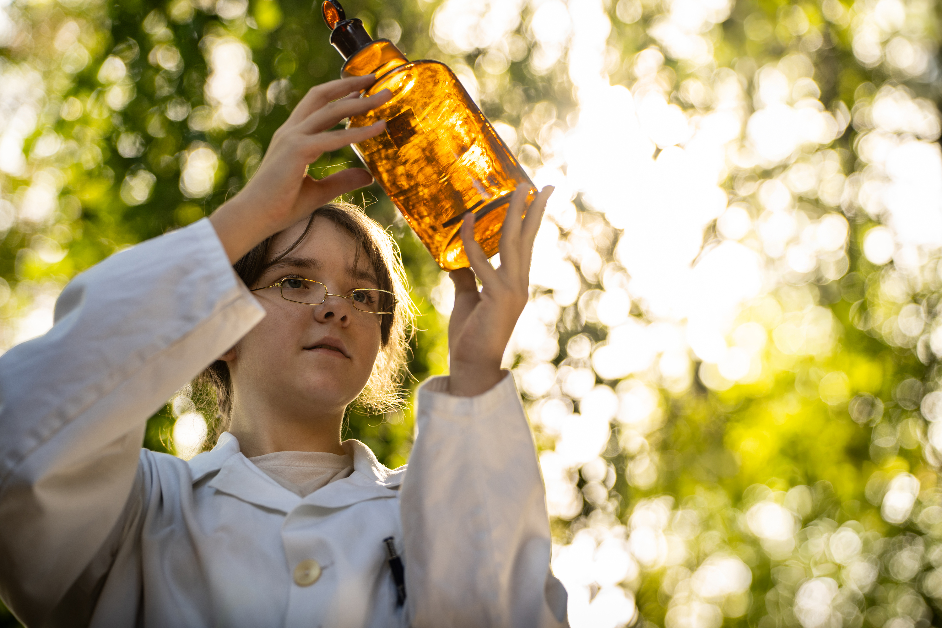 Eine weibliche Jugendliche schaut auf ein braunes Apothekenglas.