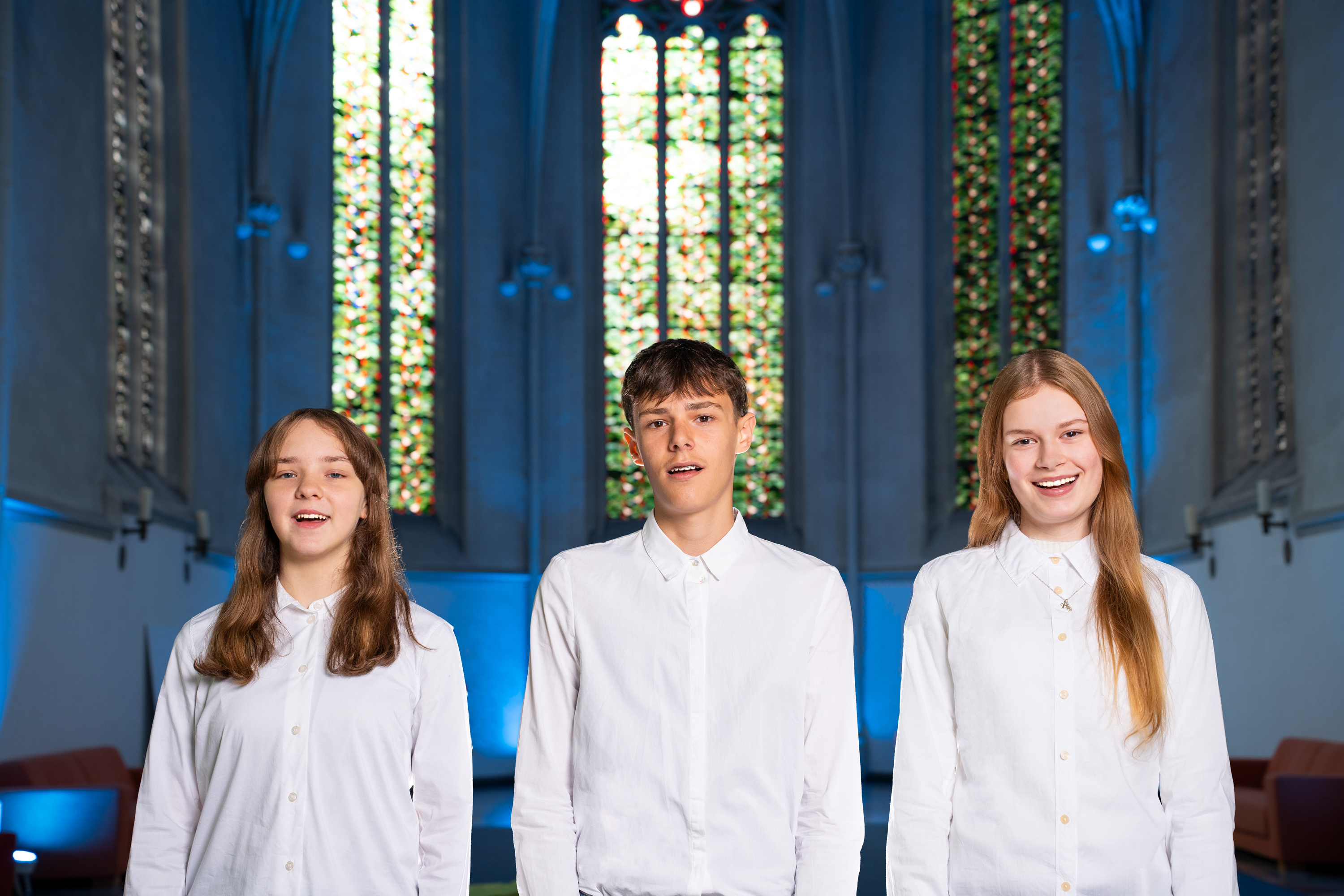 Drei Jugendliche stehen in einer Kirche