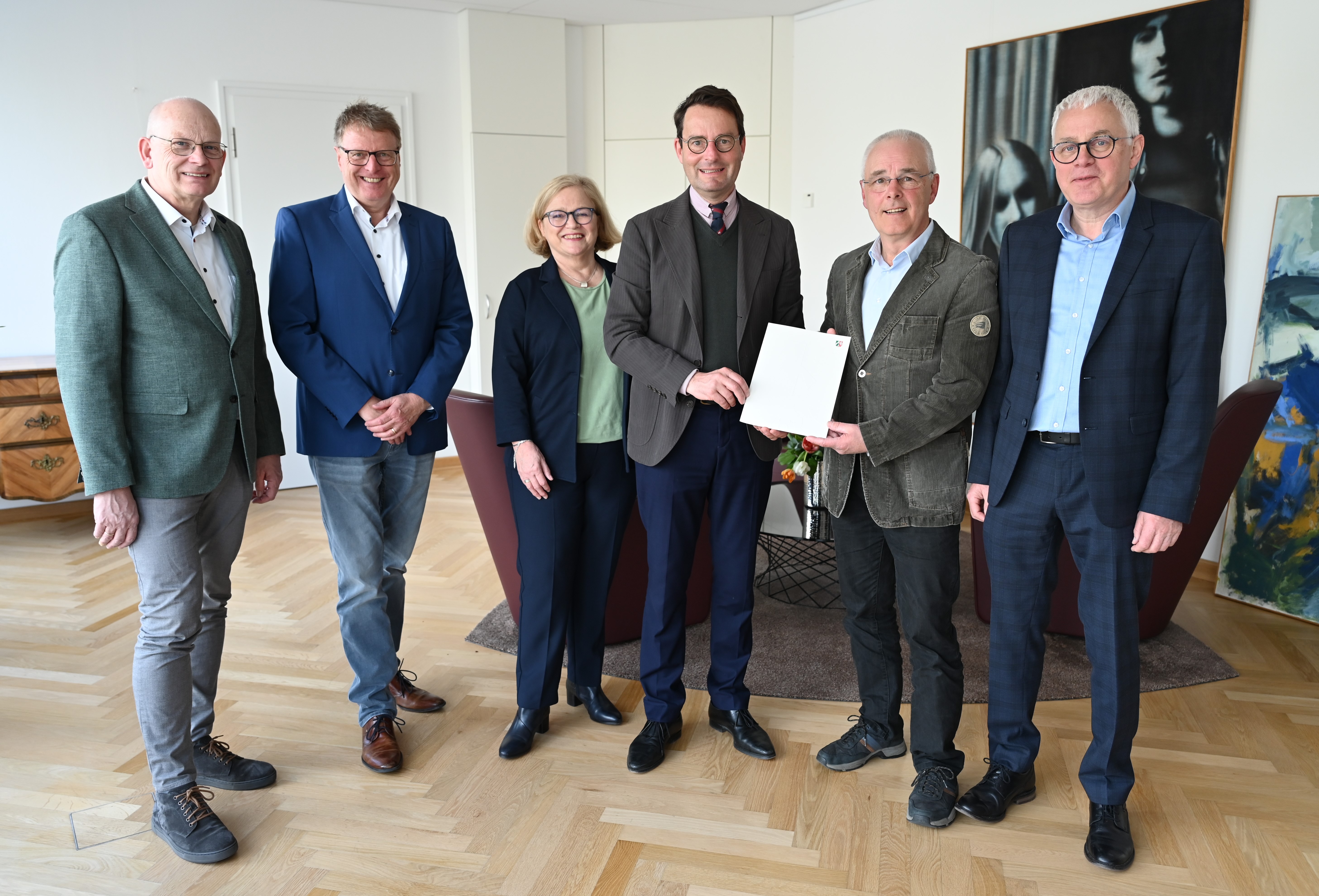 Regierungspräsident Andreas Bothe (4. v. l.) übergibt die Urkunde zur Anerkennung der „Emsdettener Stiftung für Frieden und Völkerverständigung“ an den Stiftungsvorstand.