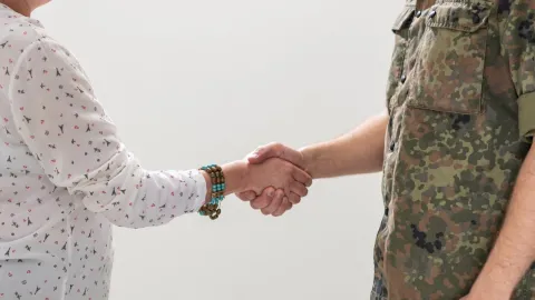 Die Abbildung zeigt eine Zivilperson und eine Person in Bundeswehruniform, die sich die Hände schütteln
