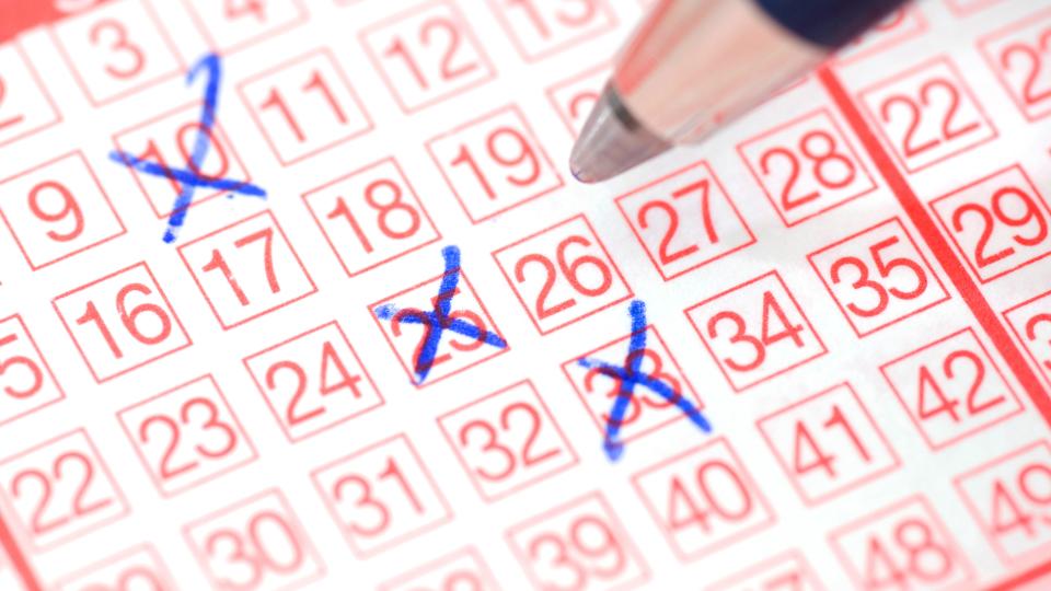 Ein Stift setzt Kreuze auf einem Lotterieschein. 