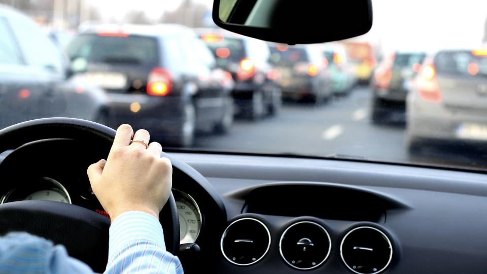 Hand am Steuer eines Autos im Stau