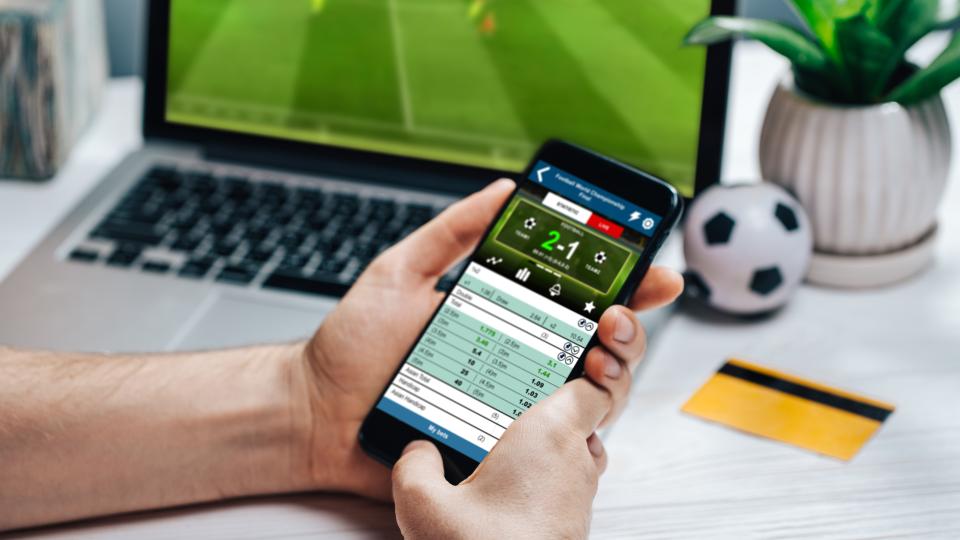 Eine Person wettet mit einem Smartphone auf ein Fußballspiel