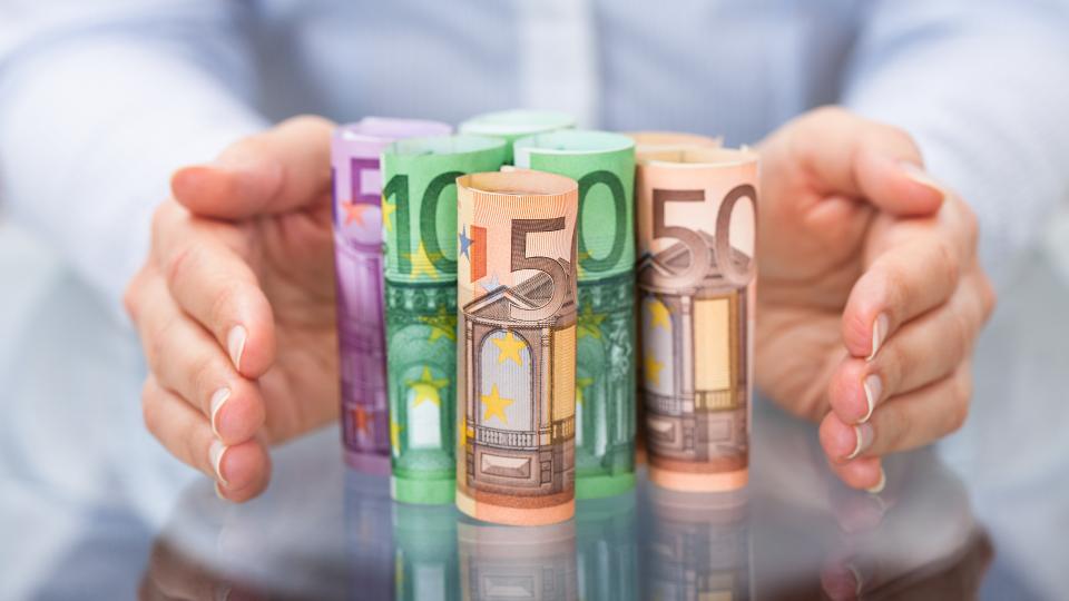 Zwei Hände stehen schützend um Bargeld