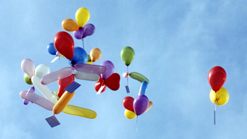 Bunte Ballons mit Postkarten steigen in den Himmel