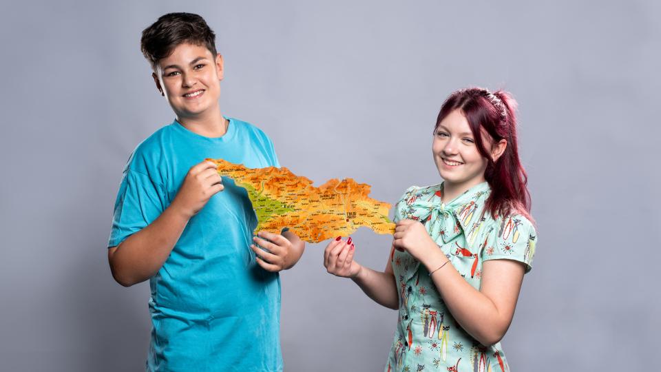 Zwei Jugendliche halten die Kartenumrisse von Georgien