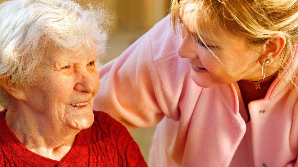 Eine ältere Dame und eine jüngere Dame lächeln sich an