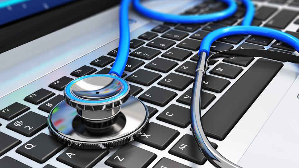Ein Stethoskop liegt auf einer Laptop-Tastatur