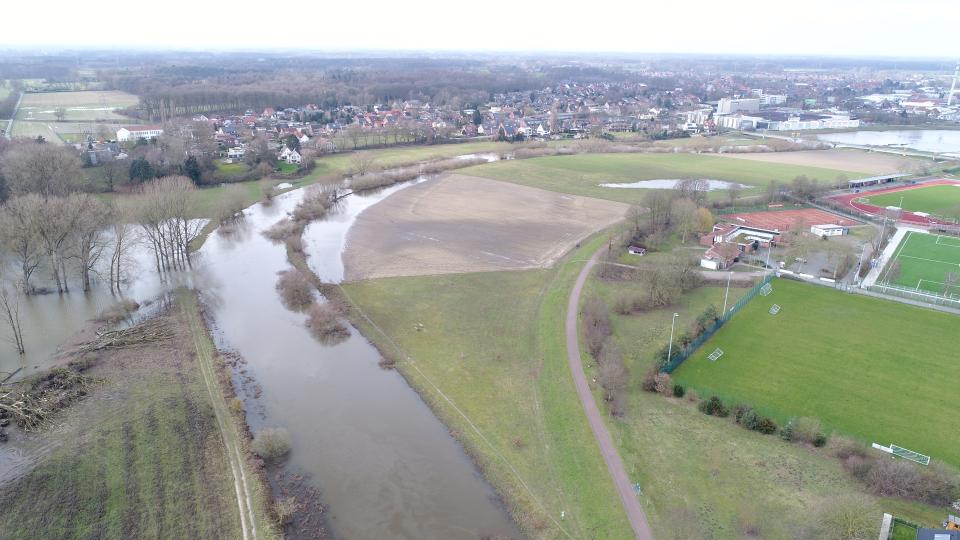 Luftbild mit Blick auf die Baufläche vor Beginn der Arbeiten bei einem Pegelstand von 6,30 m. Hier sieht man deutlich, dass die ursprüngliche Aue der Ems noch nicht unter Wasser steht. 