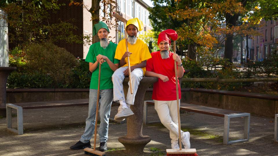 Drei männliche Jugendliche sind als Märchenzwerge verkleidet und halten Besen.