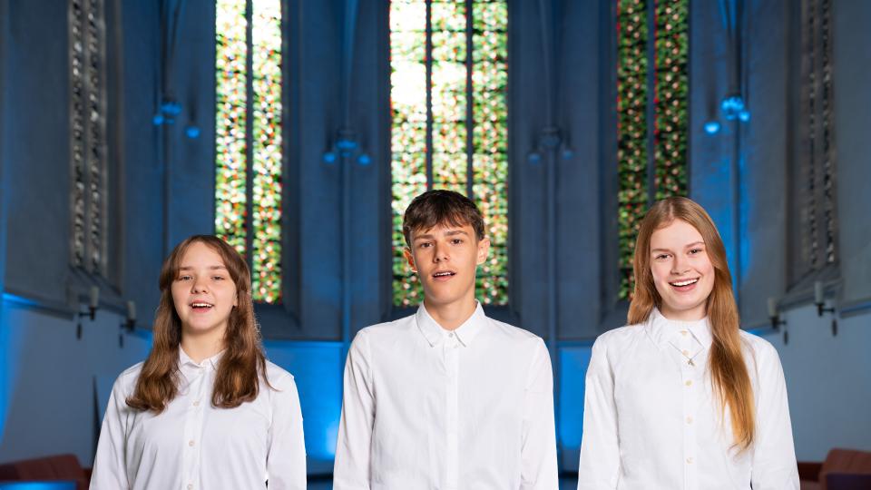 Drei Jugendliche stehen in einer Kirche