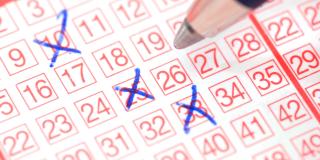 Ein Stift setzt Kreuze auf einem Lotterieschein. 