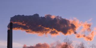 Qualm weht aus einem industriellen Schornstein im Sonnenuntergang