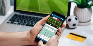 Eine Person wettet mit einem Smartphone auf ein Fußballspiel