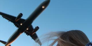 Eine Frau schaut auf ein über ihr fliegendes Flugzeug