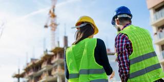 Zwei Personen mit Sicherheitskleidung vor Baustelle