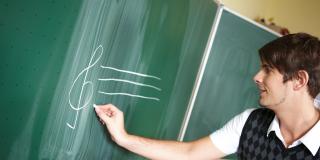 Lehrer schreibt an eine Tafel