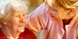Eine ältere Dame und eine jüngere Dame lächeln sich an