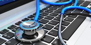 Ein Stethoskop liegt auf einer Laptop-Tastatur