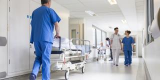 Ein Pfleger schiebt ein Bett durch einen Krankenhausflur