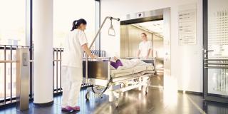 Ein Krankenhausbett wird in einen Aufzug geschoben