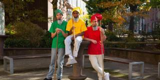 Drei männliche Jugendliche sind als Märchenzwerge verkleidet und halten Besen.