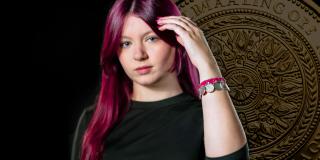 Eine weibliche Jugendliche hälte den linken Arm nach vorne. Dort befindet sich ein Armband mit Münzen. Im Hintergrund ist eine große Münze zu sehen.