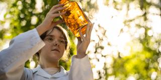 Eine weibliche Jugendliche schaut auf ein braunes Apothekenglas.