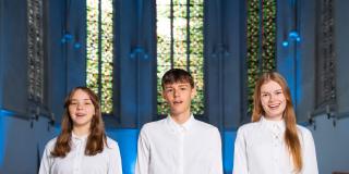 Drei Jugendliche stehen in einer Kirche