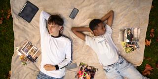 Zwei Jugendliche liegen auf einer Decke. Um sich herum sind Fotos der anderen Projekte verteilt.